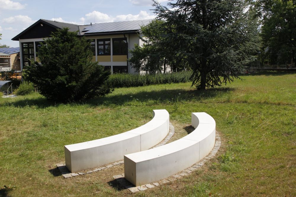 Grünes Klassenzimmer mit zwei abgerundeten Betonbänken